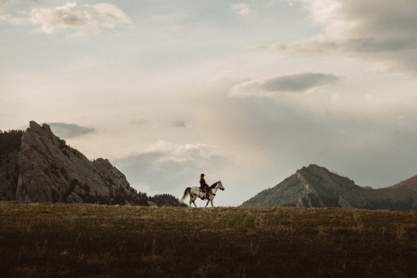 A person riding a horse across a mountainous landscape