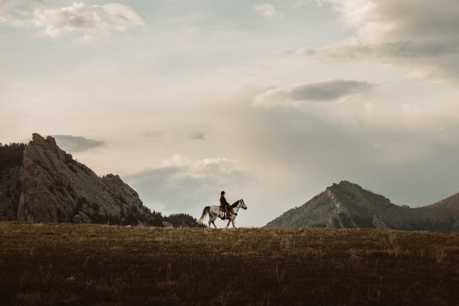 A person riding a horse across a mountainous landscape