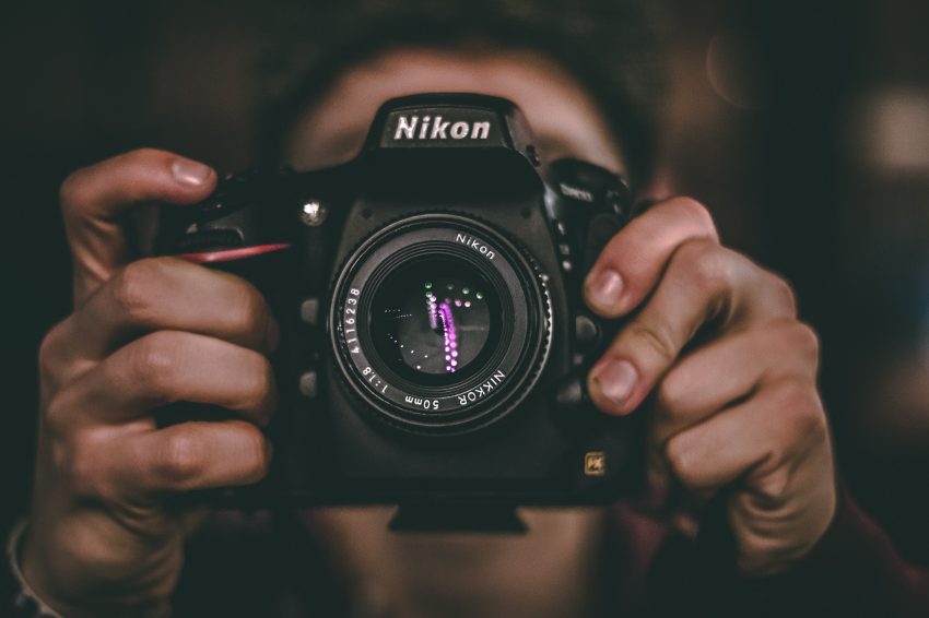 Man holding Nikon camera with both hands in front of his face