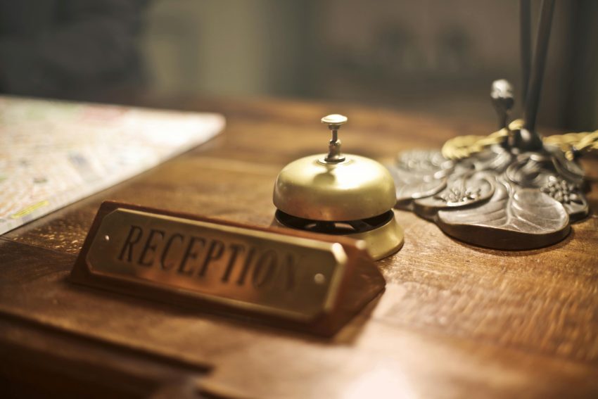 reception sign and bell positioned on wooden desk